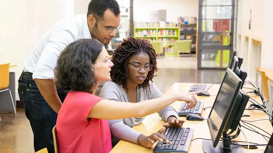 Group of three teachers looking at a computer screen